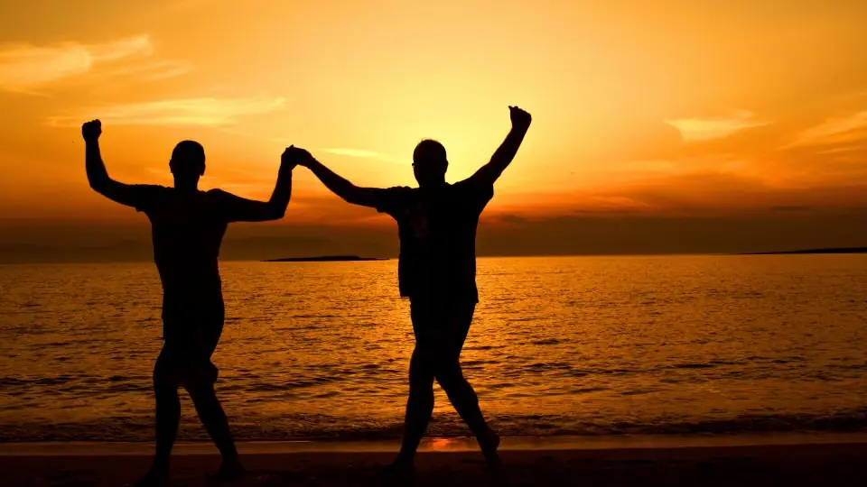 Plan cul ou rencontre classique: deux silhouettes lèvent les bras au coucher du soleil